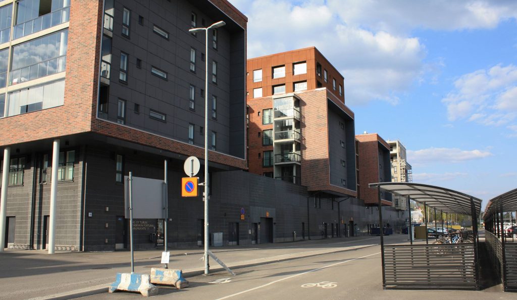 Uusia, punatiilellä verhottuja Logomon kerrostaloja rivissä aurinkoisena kesäpäivänä asuinalueella Pohjolassa Turussa.