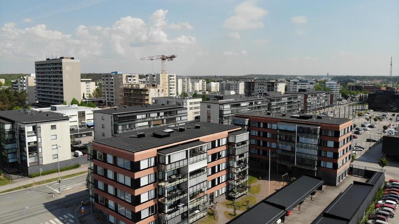 Raision keskustan moderneja kerrostaloja, asfalttiteitä ja nostokurki.