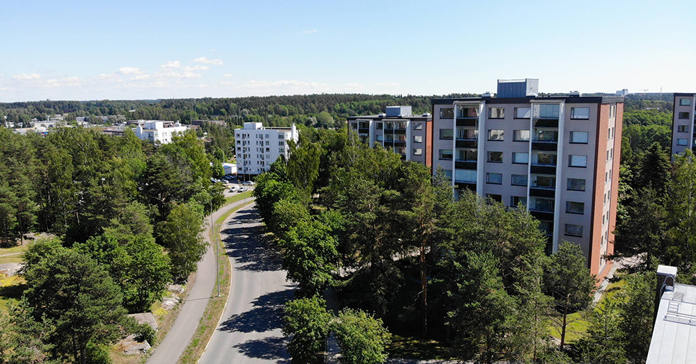 Kerrostaloja, asfalttitie ja pyörätie vehreiden puiden seassa asuinalueella nimeltä Ilpoinen Turussa.