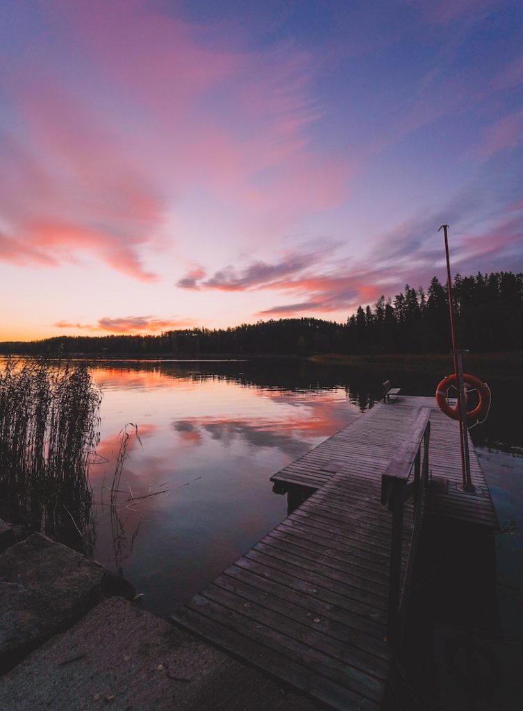 Littoistenjärven laituri tyynellä järvellä upean värisen taivaan heijastuessa järven pintaan.