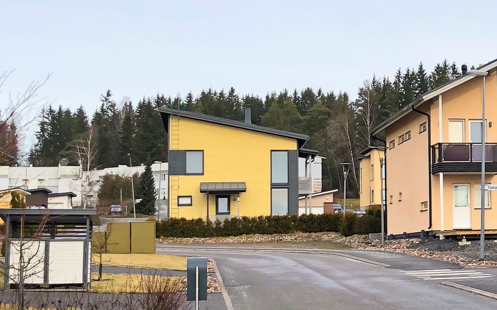 Moderni keltainen pientalo ja muita moderneja taloja Kaarinassa Voivalan asuinalueella.