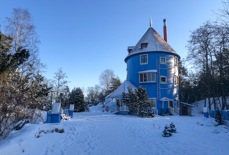 Muumimaailman pyöreä sininen muumitalo lumisessa talvimaisemassa.