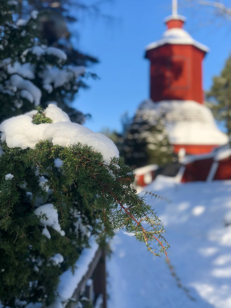 Punainen kirkkorakennus ja havunoksia Merimaskussa Naantalissa.