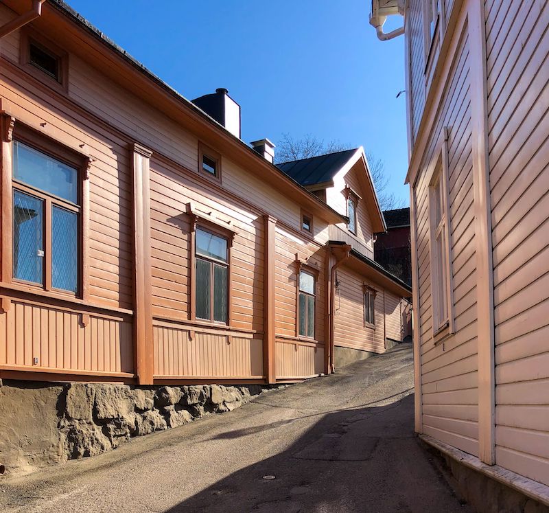 Vaaleanpunaiset puutalot reunustavat kapeaa katua Naantalin vanhassakaupungissa