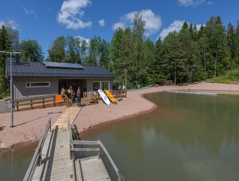 Falkinkosken saunarakennus, jonka edustalla SUP-lautoja, laituri ja lampi.