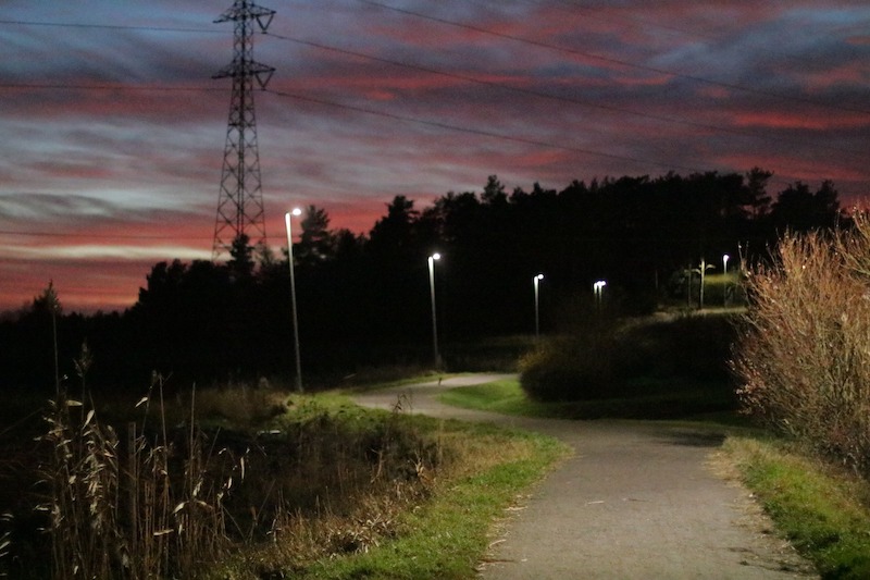 Valaistu kuntorata ja takana kohoava synkkä metsä auringonlaskun aikaan.