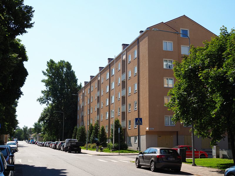 Vanha kivinen kerrostalo Turun Marissa. Kadun varressa auroja parkissa.