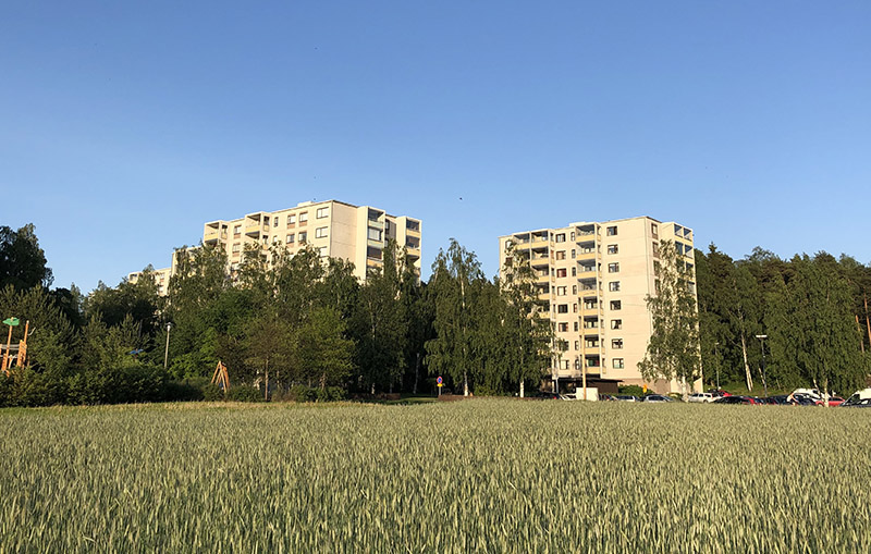 Peltomaisema etualalla ja kerrostaloja taka-alalla Turun Härkämäessä