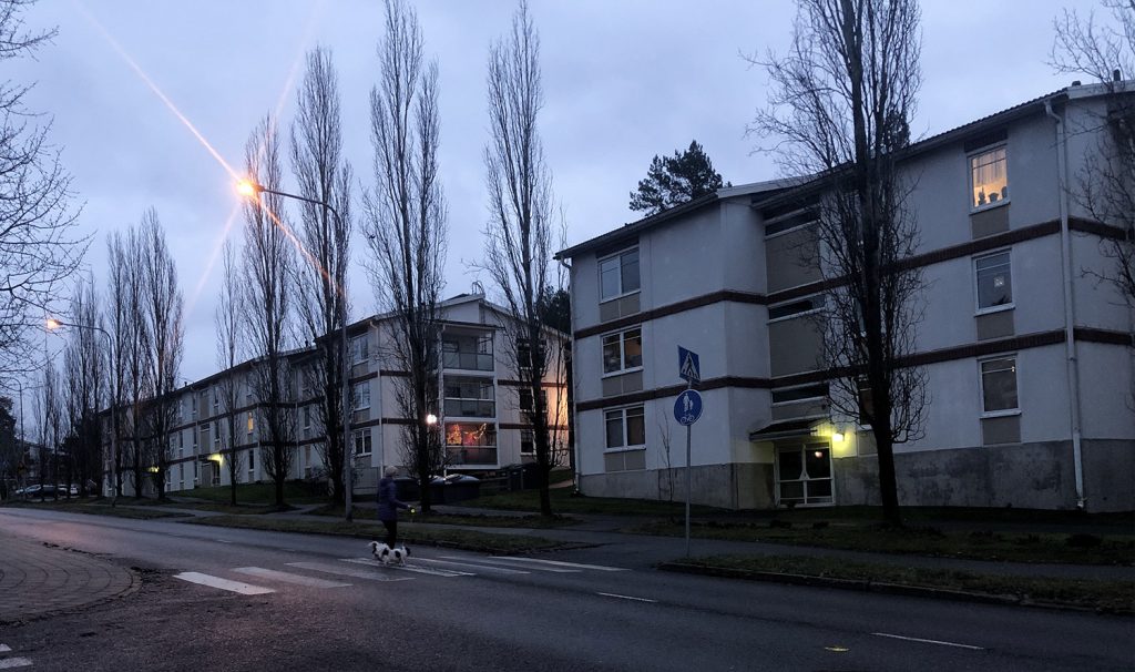 Turun Teräsrautelan valkoisia pienkerrostaloja. Suokatietä ylittämässä koira ja sen ulkoiluttaja marraskuisena sadepäivänä.