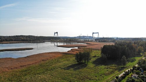 Ilmakuva Raisionlahdelle Kaanaan naapurustossa. Etualalla puita ja niitty. Taka-alalla Pernon telakka ja risteilyalus.