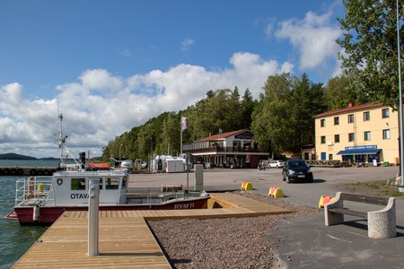 Vene laiturissa Röölän satamassa Naantalin saaristossa. Takana on vanhoja rakennuksia. Taustalla puita ja meri.