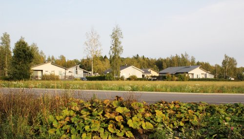 Etualalla autotie ja pelto. Takana Paikkarin omakotitaloalue Raisiossa.