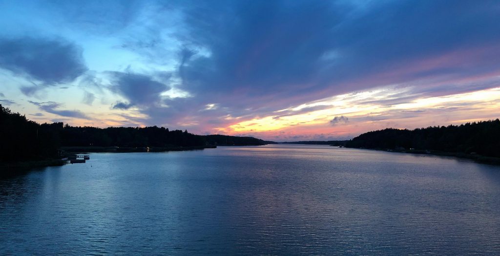 Näkymä Satavan ja Hirvensalon yhdistävältä sillalta merelle, jossa näkyy manner siluettina molemmin puolin ja auringonlaskun värjäämä taivas.