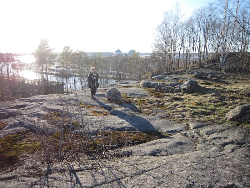 Nainen kävelee Korppolaismäellä ja tuastalla siintää Turun linna ja Aurajoki. 