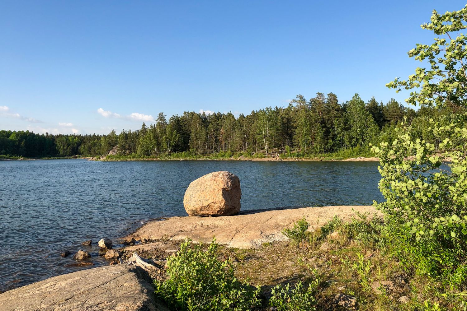 Etualalla kallio ja iso kivi, taustalla Haunisten altaan järvimaisemaa.